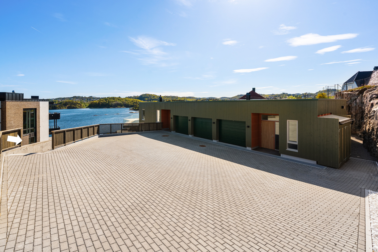 Fra felles gårdsplass viser pilen til venstre i bildet trapp, og adkomst til leiligheten i første etasje. Fast plass i en av de tre garasjene.