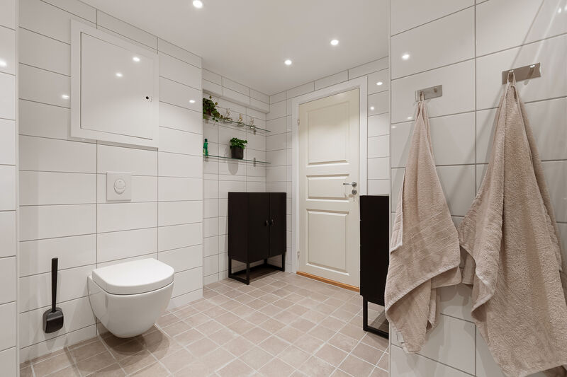 Badet er utstyrt med dusjhjørne, innfellbare dusjdører, servant, veggmontert WC og opplegg for vaskemaskin.